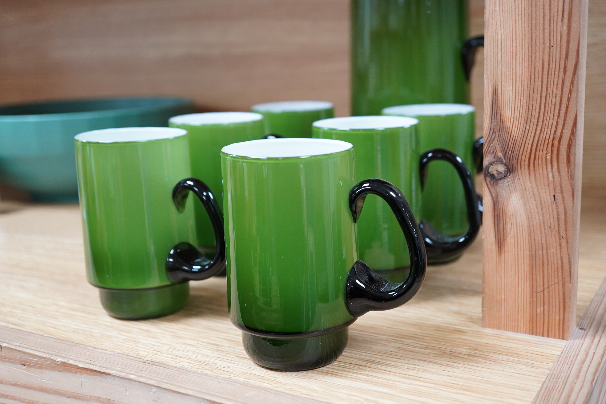 Michael Bang for Holmegaard glass, a green cased jug and six mugs with stepped bases, largest 20cm high